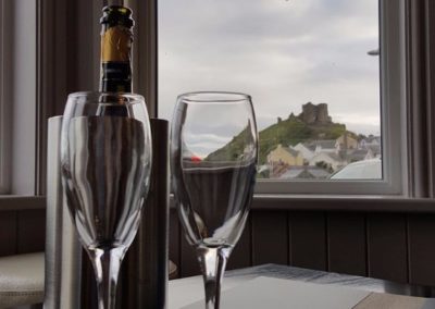 A bottle of champagne with a view of Criccieth Castle in the background.