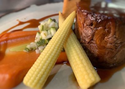 A restaurant meal of beef with baby corn, carrots and gravy