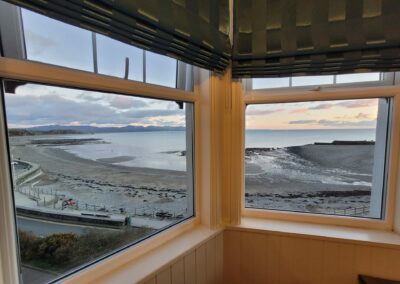 A corner window at dusk with views of the beach.